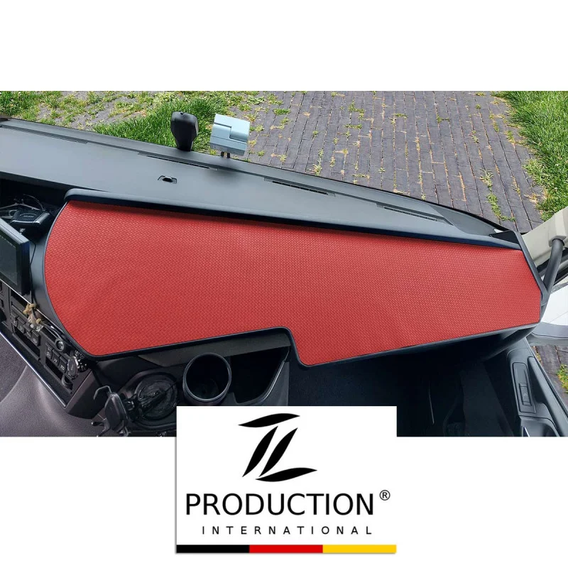 Das LKW-Tisch für den Volvo FH ist elegant mit einer roten Antirutschmatte bedeckt. Der Blick umfasst Teile der Windschutzscheibe und des Seitenspiegels. Ein Logo am unteren Rand zeigt „TL Production International“, während die Matte einen starken Kontrast zum dunklen Innenraum bildet.